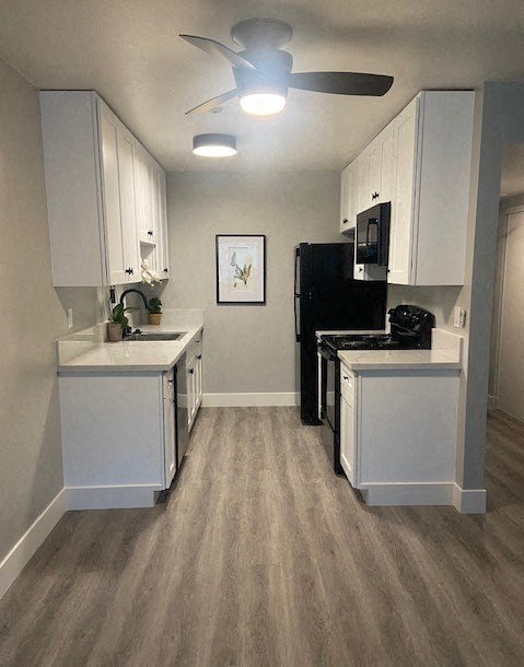 a kitchen with white cabinets and black appliances